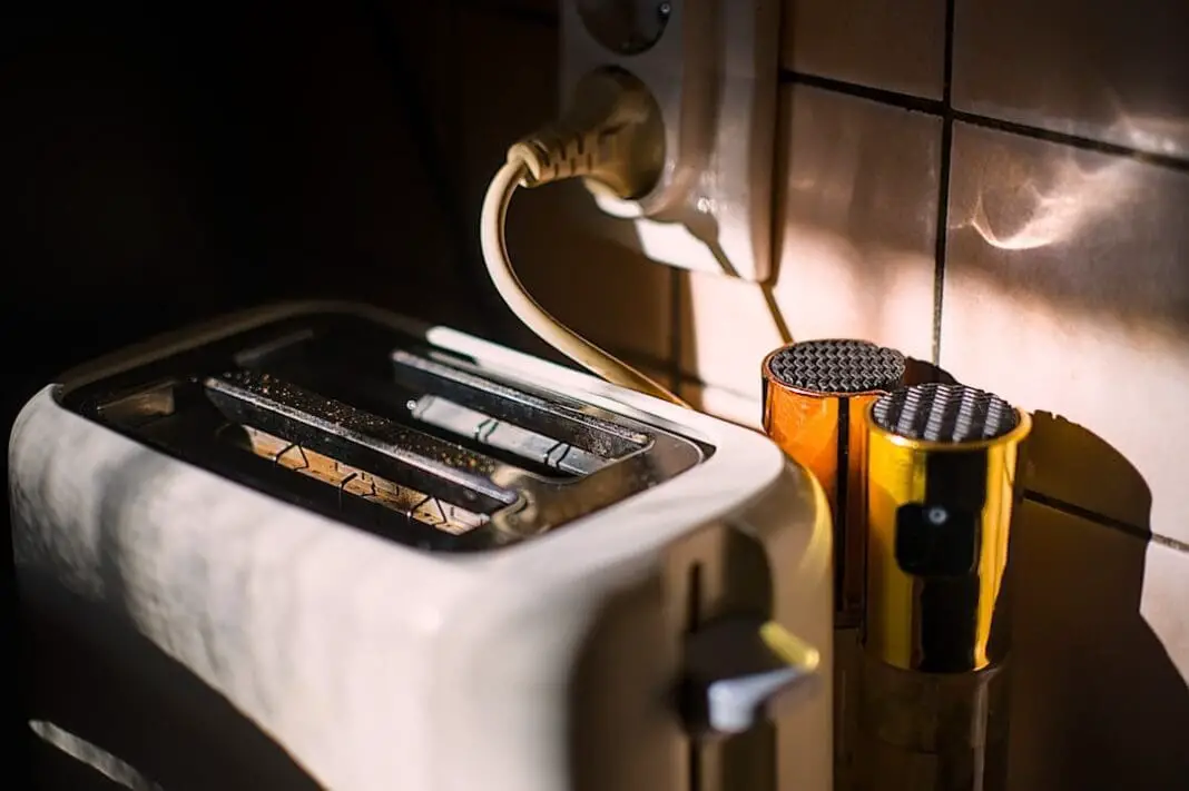 A toaster and mugs sit near a power outlet.