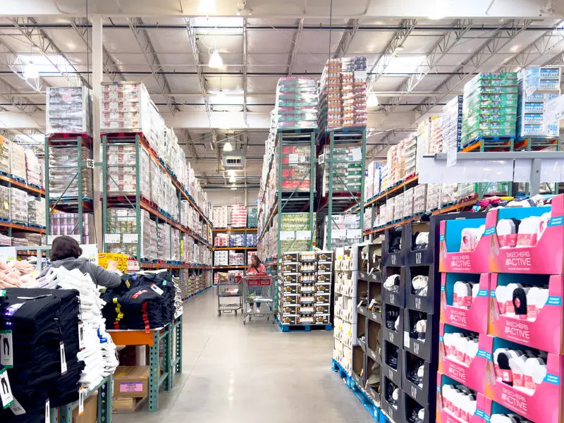 The interior of a Costco Wholesale store, features tall aisles filled with bulk goods and