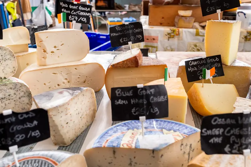 A display of tasty looking cheeses for sale a local farmers market, the cheese in the foreground are oput of focus to provide