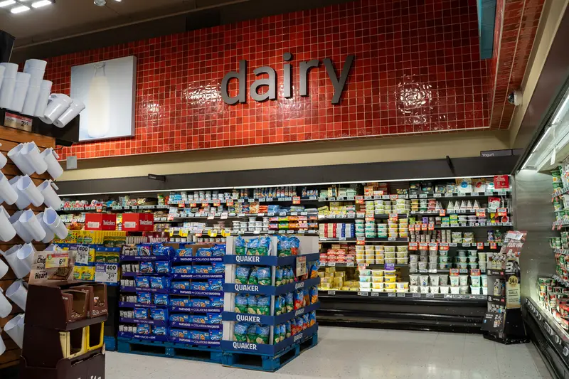Dairy products aisle with yogurt and milk display in supermarket.
