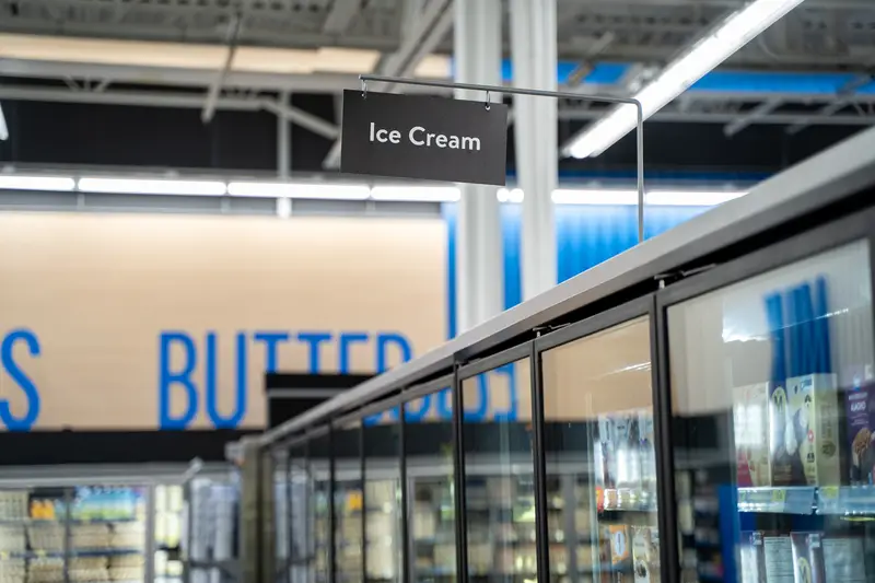 View of ice cream sign above refrigerated freezer aisle.